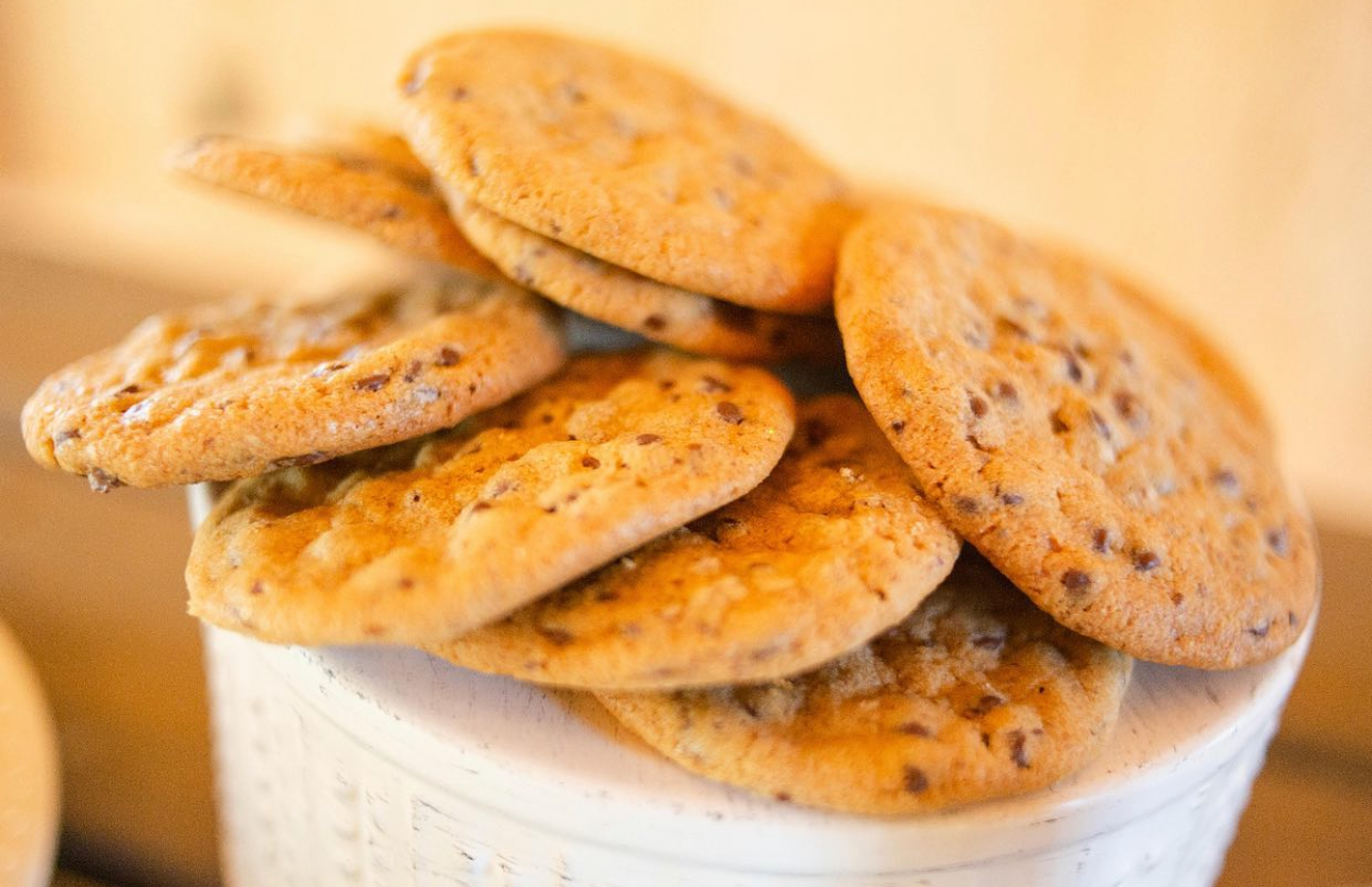 A bowl filled with chocolate chip cookies stacked on top of each other.