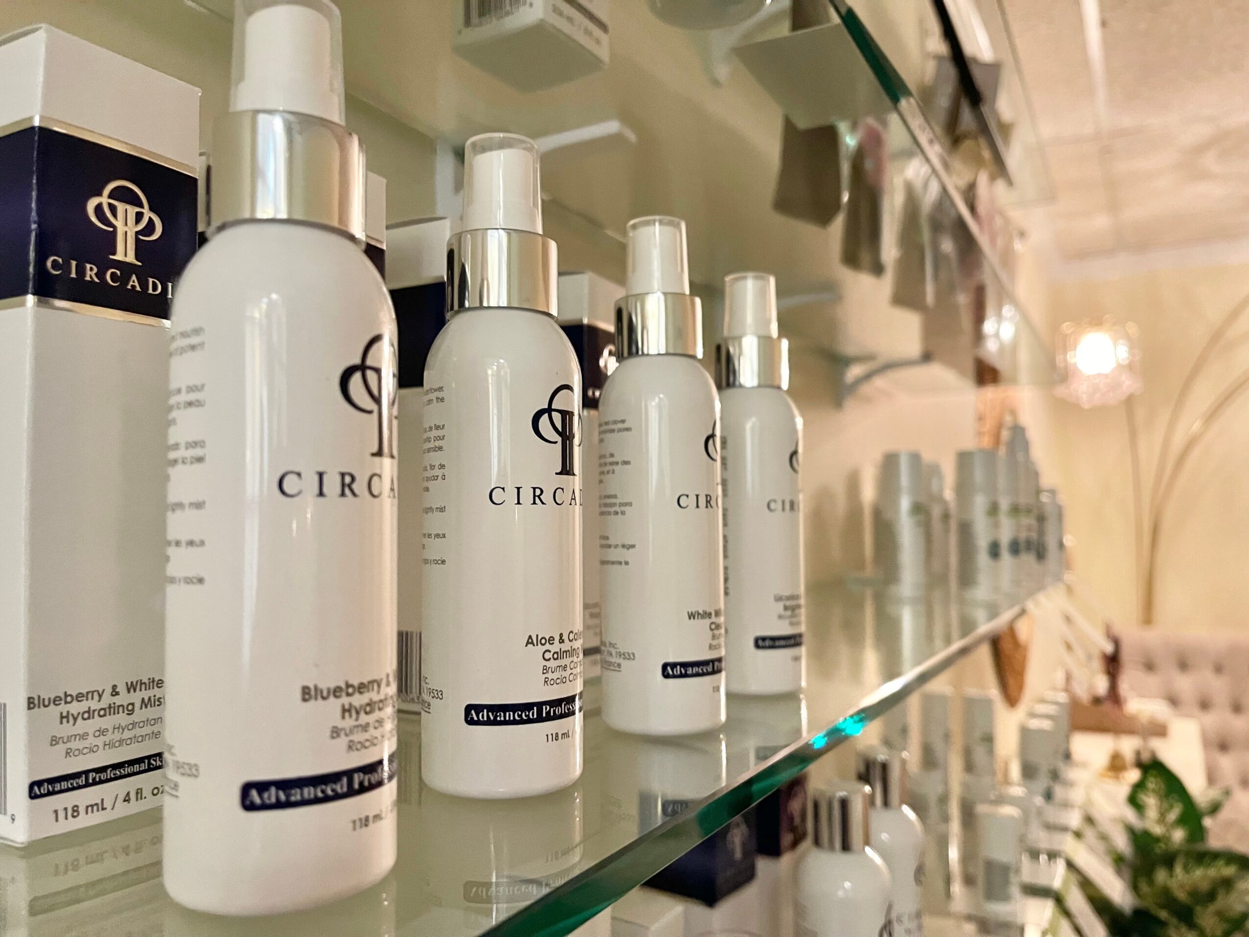 Row of white bottles with pump dispensers on a glass shelf, with a blurred background of store interior.