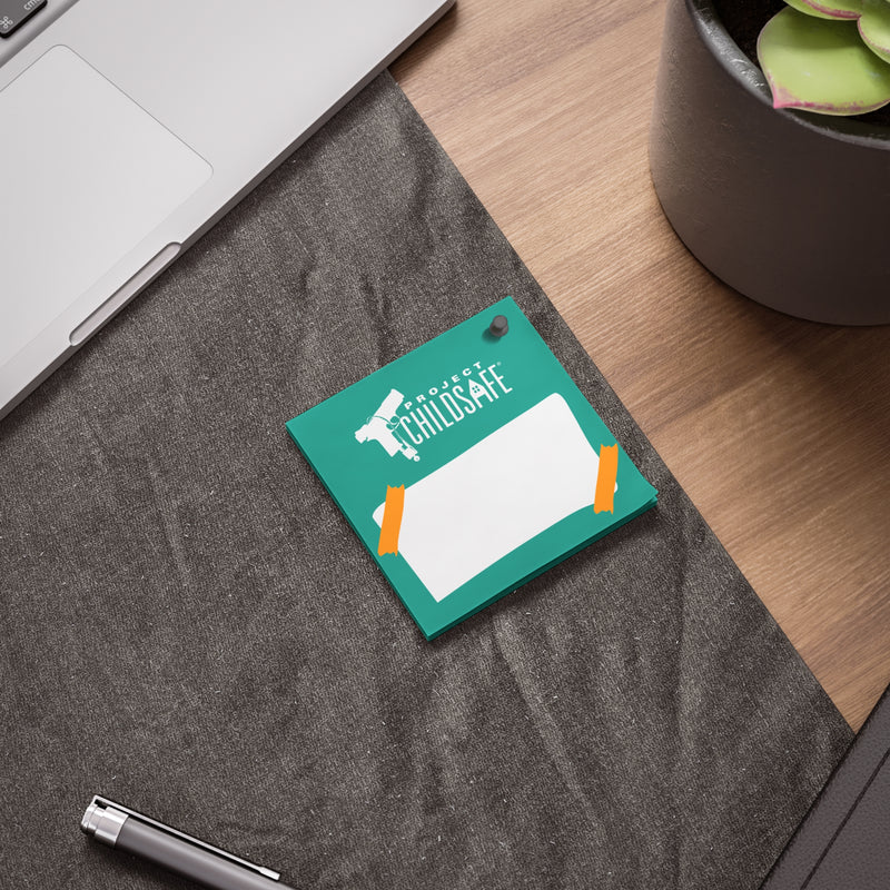 A teal-colored card with the word 'CHILDSAFE' and a safety helmet icon, placed on a desk near a laptop and a plant.