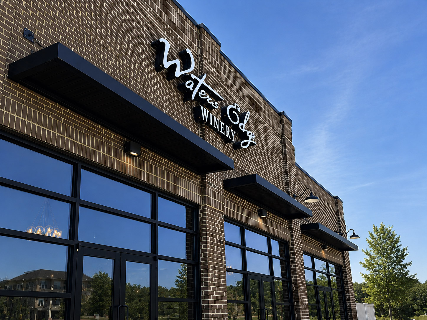 Brick building with large windows and a sign reading 'Waterfall Winery' against a blue sky.