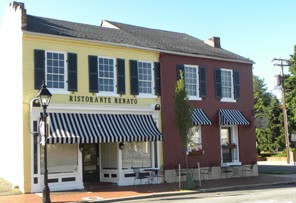 Two-story building with yellow and red sections, striped awnings, and a sign reading 'Ristorante Ellato'.