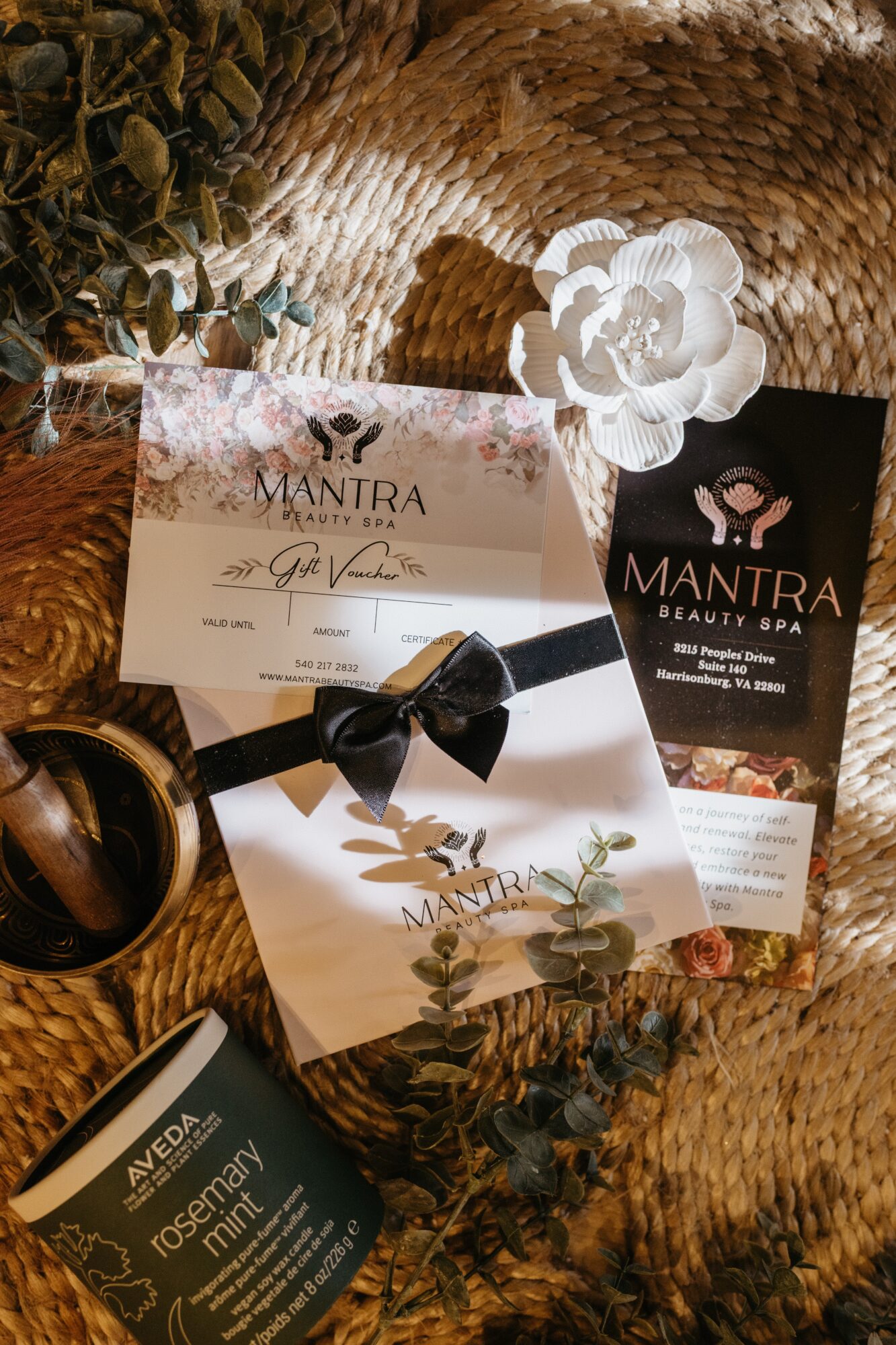 Arrangement of beauty spa and gift certificates with flowers and decorative items on a woven surface.