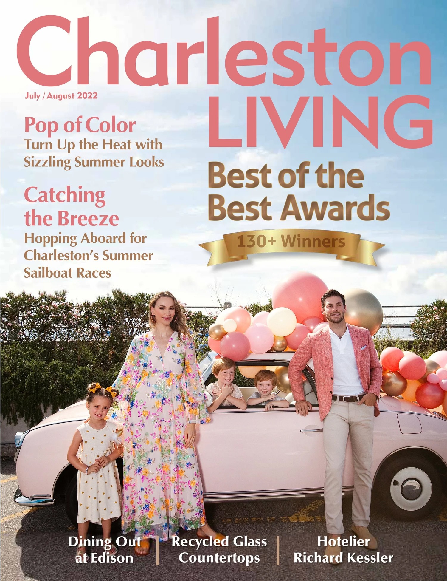 People standing next to a pink car decorated with balloons outdoors, with a woman, children, and a man smiling.