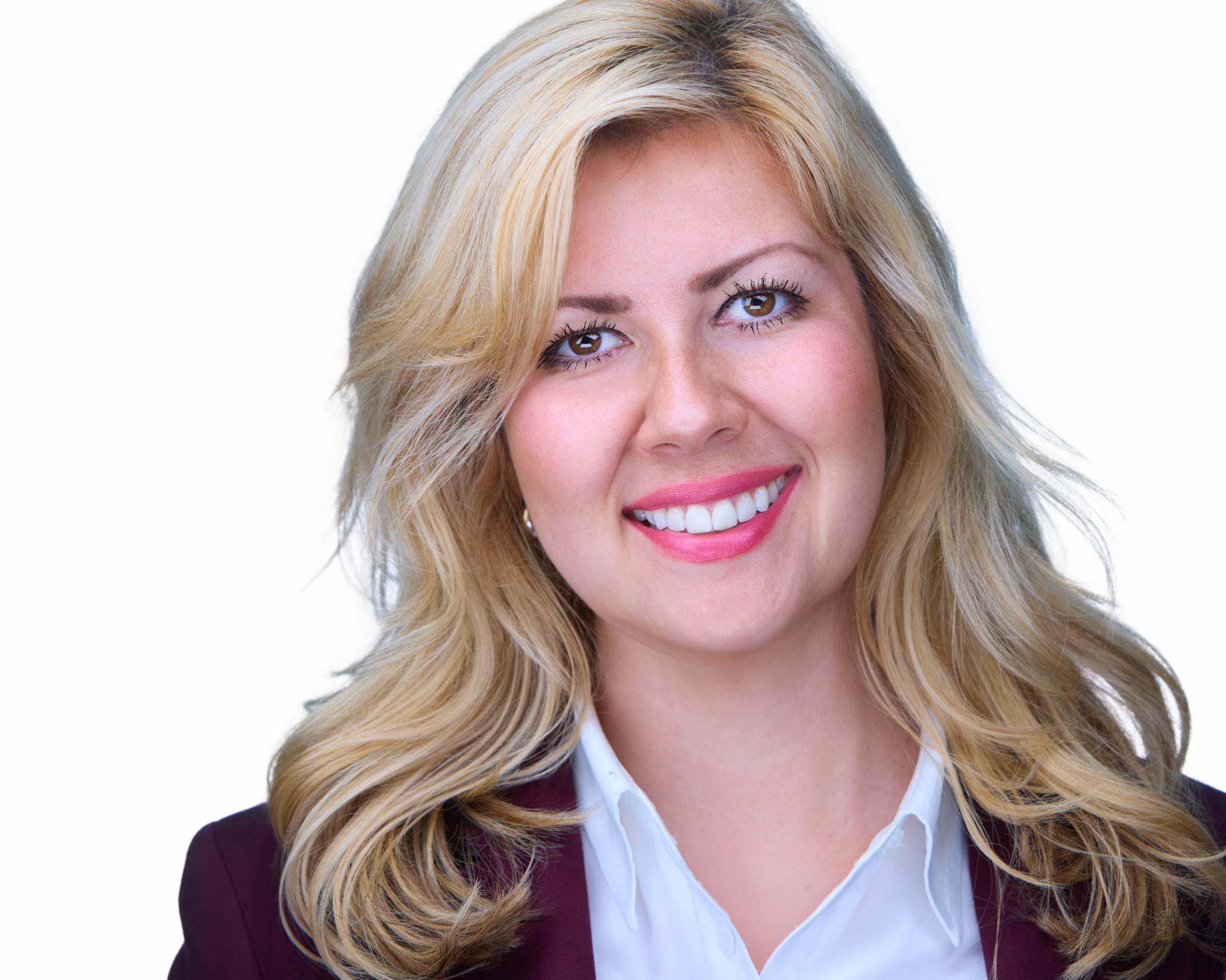 Woman with blonde hair smiling, wearing a white shirt and dark blazer, against a white background.