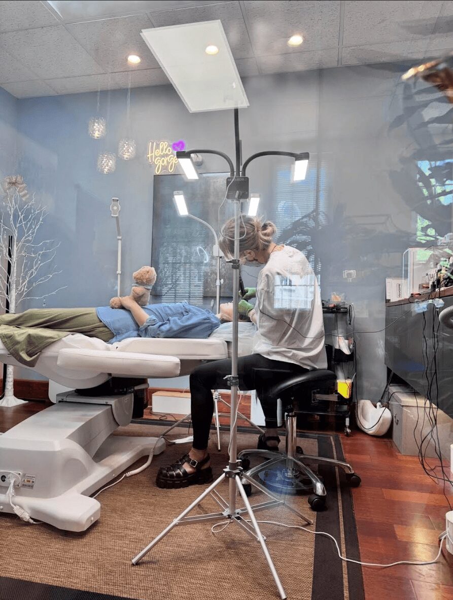 Medical professional with a mask and gloves attending to a patient lying on a hospital bed in a clinical room.
