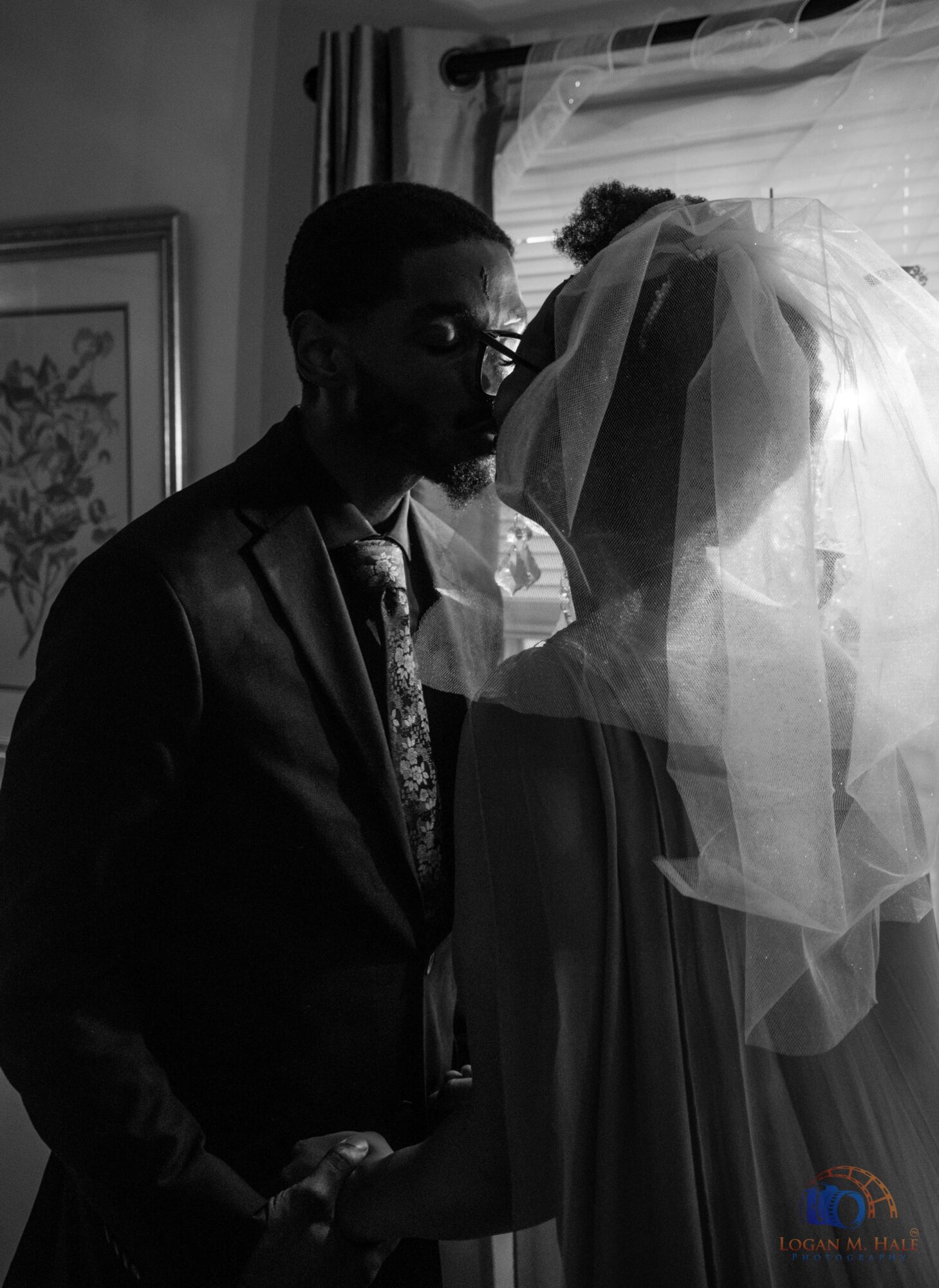 Two people, a man and a woman, face each other near a window with curtains, with a veil covering the woman's face.
