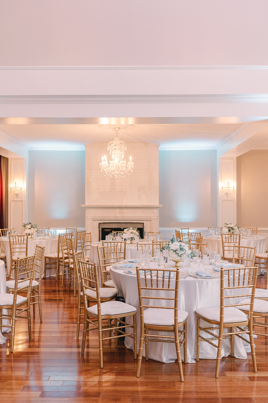 Elegant banquet hall with round table, gold chairs, chandelier, and soft lighting, set for an event.