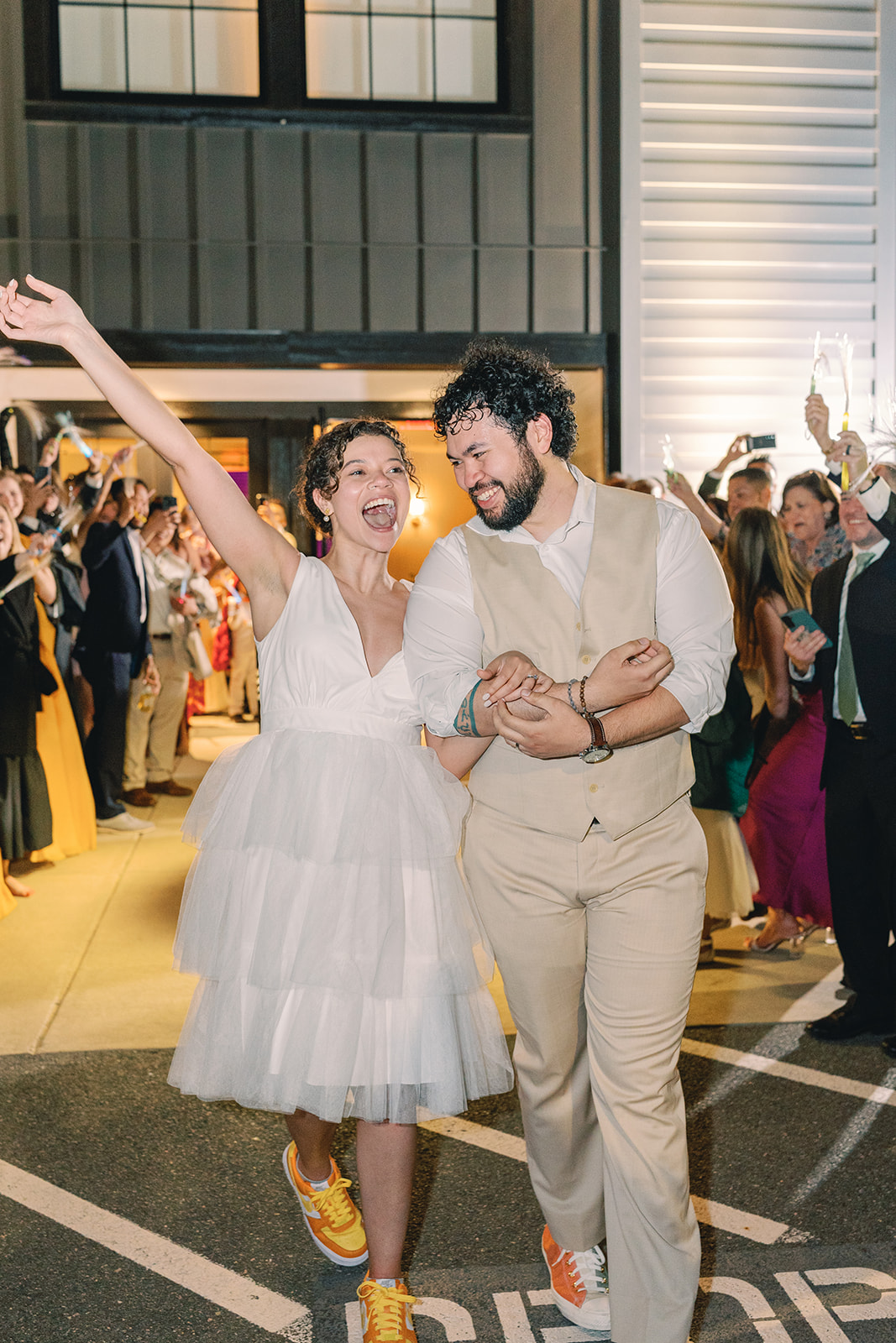 A joyful couple dancing at a celebration, surrounded by other guests, with a bright, lively atmosphere.