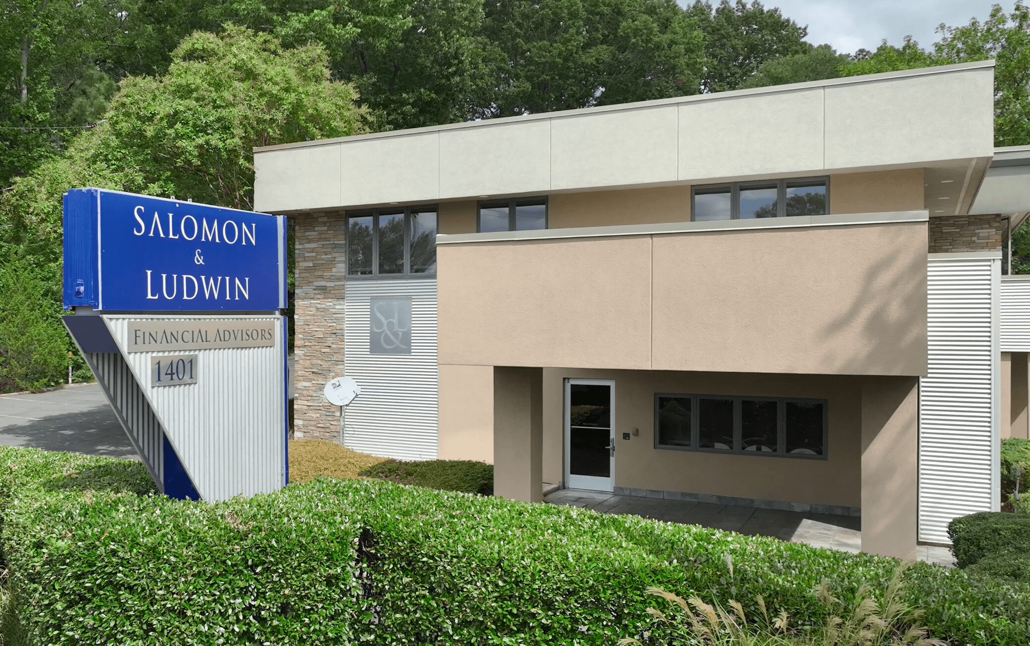 Building with a sign reading Salomon Ludwin, surrounded by greenery, with a modern architectural design.